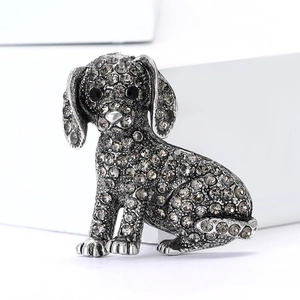 Broche chien vintage argentée avec strass gris foncé et nez en perle sur fond blanc