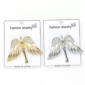Detail of angel wing brooches with sparkling rhinestones in gold and silver finish