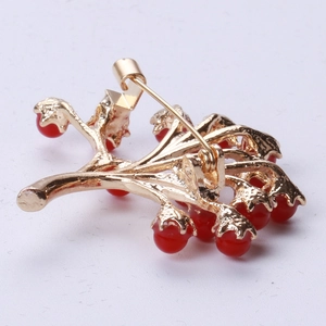 Détail de la broche feuille avec perles rouges montrant l'épingle et le fermoir au dos