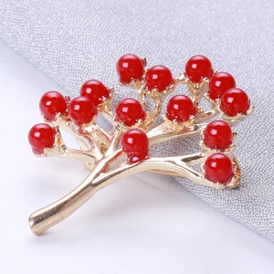 Détail macro de la broche branche en alliage doré avec accents de perles rouges