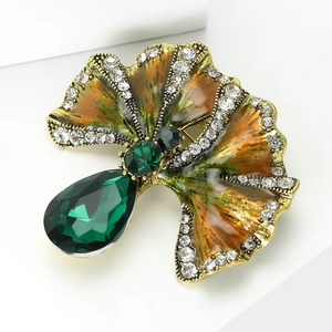 Macro shot of ginkgo leaf brooch with green gemstone and sparkling zircon crystals
