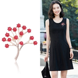Broche branche dorée avec perles rouges sur fond blanc et portée par un mannequin