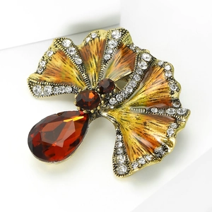 Detailed view of vintage ginkgo leaf brooch with orange enamel and red gemstones