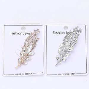 Close-up of gold and silver feather brooches with rhinestones and marquise stones