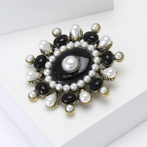 Vintage gold sunflower brooch with black gemstone and faux pearls on white stand