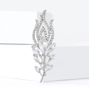 Elegant silver peacock feather brooch with sparkling rhinestones on a white podium