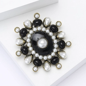Close-up of vintage baroque pearl brooch with black cabochon on white geometric block