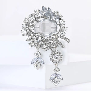 Macro detail of luxury silver brooch featuring large oval crystal and sparkling tassels