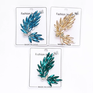 Detailed macro view of bow-shaped brooches in blue, champagne, and green crystal rhinestones