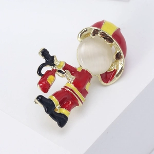 Detailed view of firefighter brooch with cat eye stone and red enamel on white pedestal