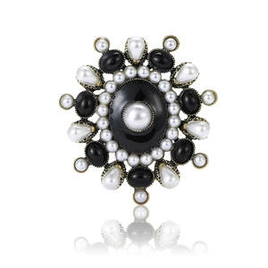 Vintage gold sunflower brooch with large black gemstone and white pearls on white background