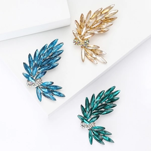 Elegant bow and wheat ear brooches with vibrant crystals on white pedestals