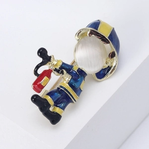 Detail of cartoon firefighter brooch with blue enamel and polished white cat-eye stone