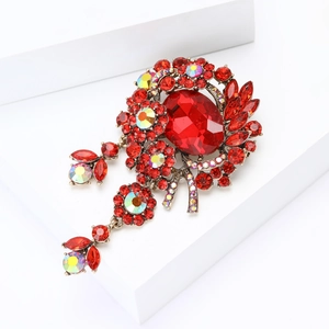 Macro detail of large red glass brooch with shimmering rhinestones on white display
