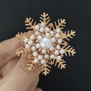 Detail shot of golden snowflake brooch with inlaid pearls and sparkling rhinestones