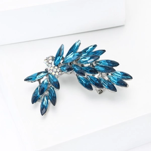 Macro detail of luxury feather brooch with navy blue crystals on a white geometric stand