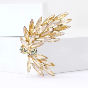 Elegant wheat stalk brooch with champagne crystals and golden base on white pedestal