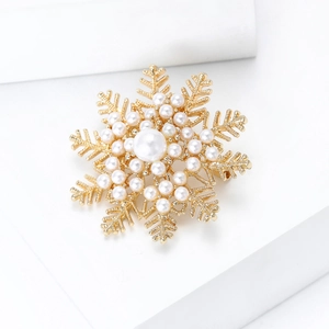 Close-up of snowflake brooch with gold metal base and white pearl inlay details