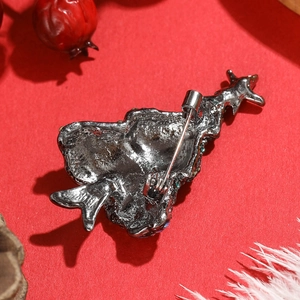 Elegant gunmetal Christmas tree brooch with diamond accents on a red festive background