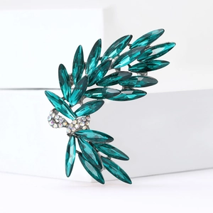 Macro shot of silver wheat brooch featuring emerald green crystals and AB rhinestones