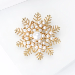 Detailed view of the golden snowflake brooch with elegant white pearls and intricate details