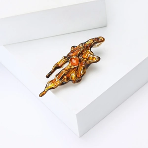 Macro shot of abstract volcanic lava brooch featuring amber enamel and gold metallic edges
