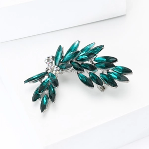 Detail of emerald green leaf brooch with marquise-cut crystals and silver finish