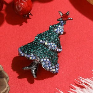 Detail view of a green rhinestone Christmas tree brooch set against festive red berries