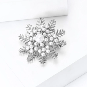 Detail of snowflake brooch with pearls and silver metal on white geometric background
