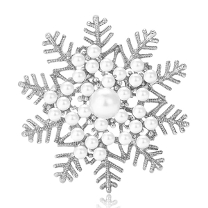Broche flocon de neige argentée avec perles blanches et cristaux sur fond blanc pur