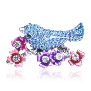 Detailed view of rhinestone encrusted bird and flower brooch with blue enamel finish