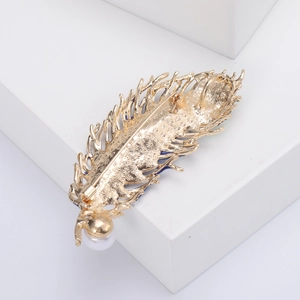 Detail of peacock feather brooch with gold finish, back pin fastener and white pearl accent