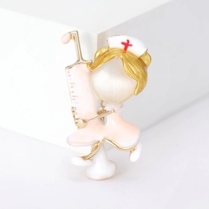 Detail of cartoon nurse brooch with pink enamel and cat-eye stone on white display