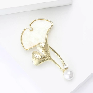 Elegante broche de hoja de ginkgo dorado con acabado de nácar y una perla blanca