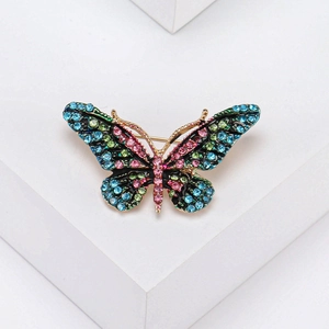 Macro detail of butterfly brooch with colorful rhinestones on a white geometric stand