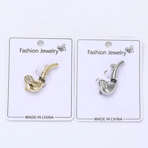 Close-up of golden and silver pipe-shaped brooches with sparkling white rhinestones