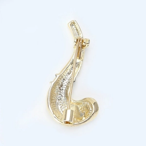 Close-up of golden pipe brooch back with fine textured metal and secure safety pin fastener