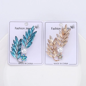 Détail macro de broches en forme de feuille avec cristaux bleus, champagne et perles