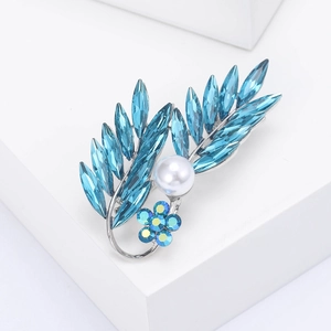 Détail de la broche en forme de feuille avec cristaux bleus et une grande perle d'imitation