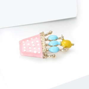 Vue macro d'une broche en émail avec pois roses, décor bleu et cadre en alliage doré