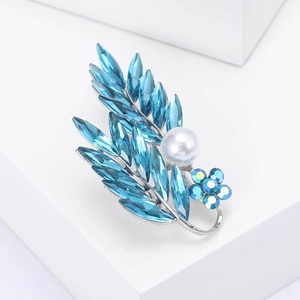 Gros plan détaillé d'une broche feuille en cristal bleu avec perle blanche sur support