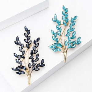 Elegant gold leaf tree brooches with navy and sky blue crystal rhinestones on white stand