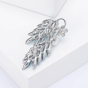 Détail macro de broche épi argentée avec cristaux bleus et une perle blanche