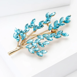 Close-up of golden leaf brooch featuring light blue marquise cut rhinestones and crystals
