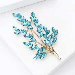 Detail of elegant gold-toned branch brooch with light blue marquise crystals