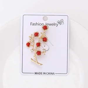 Macro detail of a vintage gold branch brooch with red beads and sparkling rhinestones