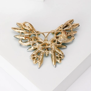 Elegant gold butterfly brooch with blue crystals and pin closure on white stand