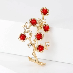 Vintage gold branch brooch with red pearls and crystals on white geometric stand