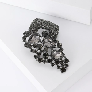 Macro shot of gunmetal brooch with grey crystals on a white geometric block
