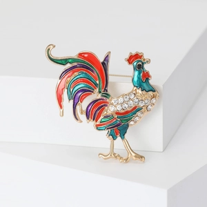 Dettaglio di una spilla a gallo colorata con ali in smalto e strass scintillanti